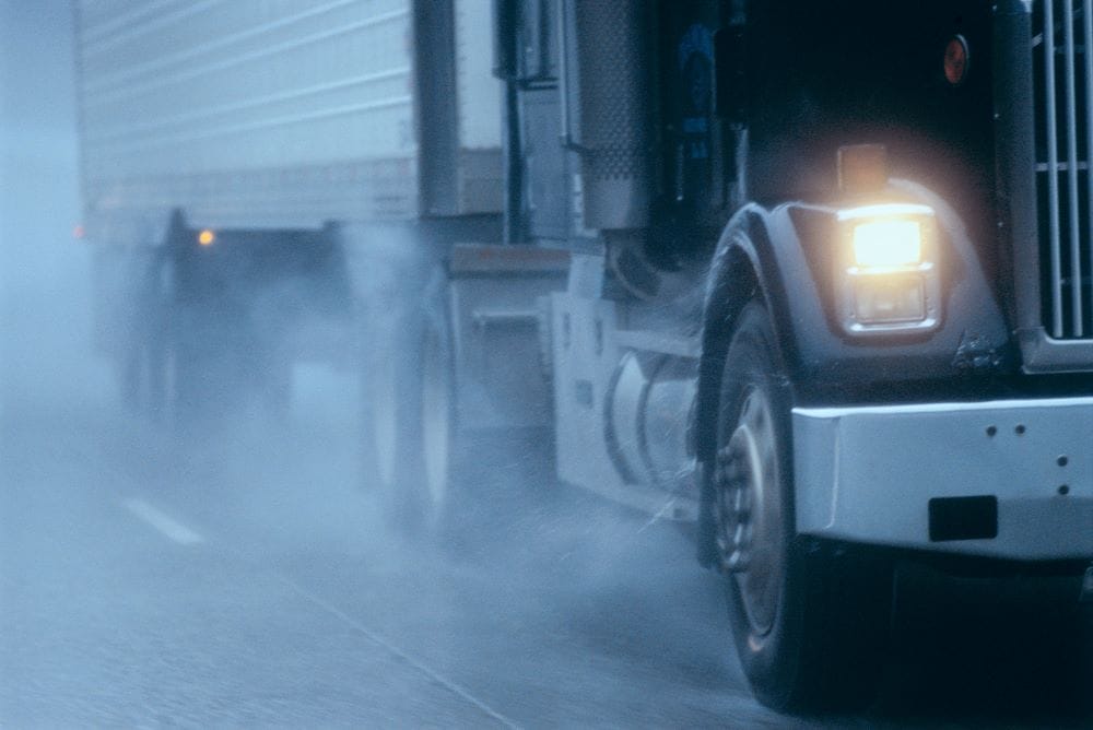 partial view of large commercial truck driving in sleet